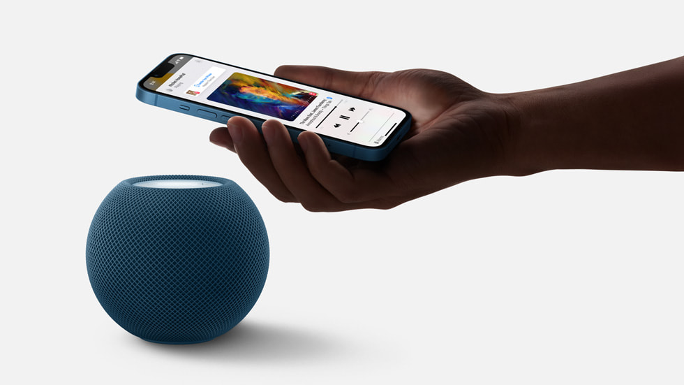 A user holds their iPhone over their HomePod speaker.