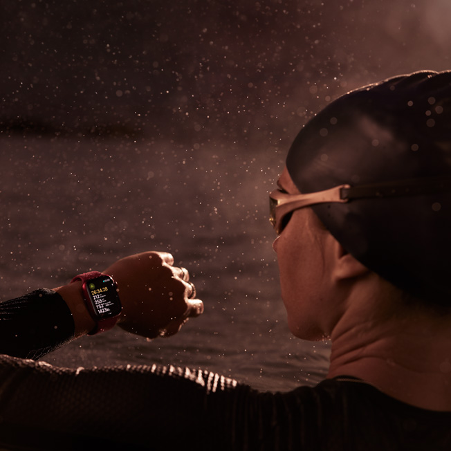 ภาพนักว่ายน้ำที่อยู่ในสระกำลังดู Apple Watch ของตนเอง 