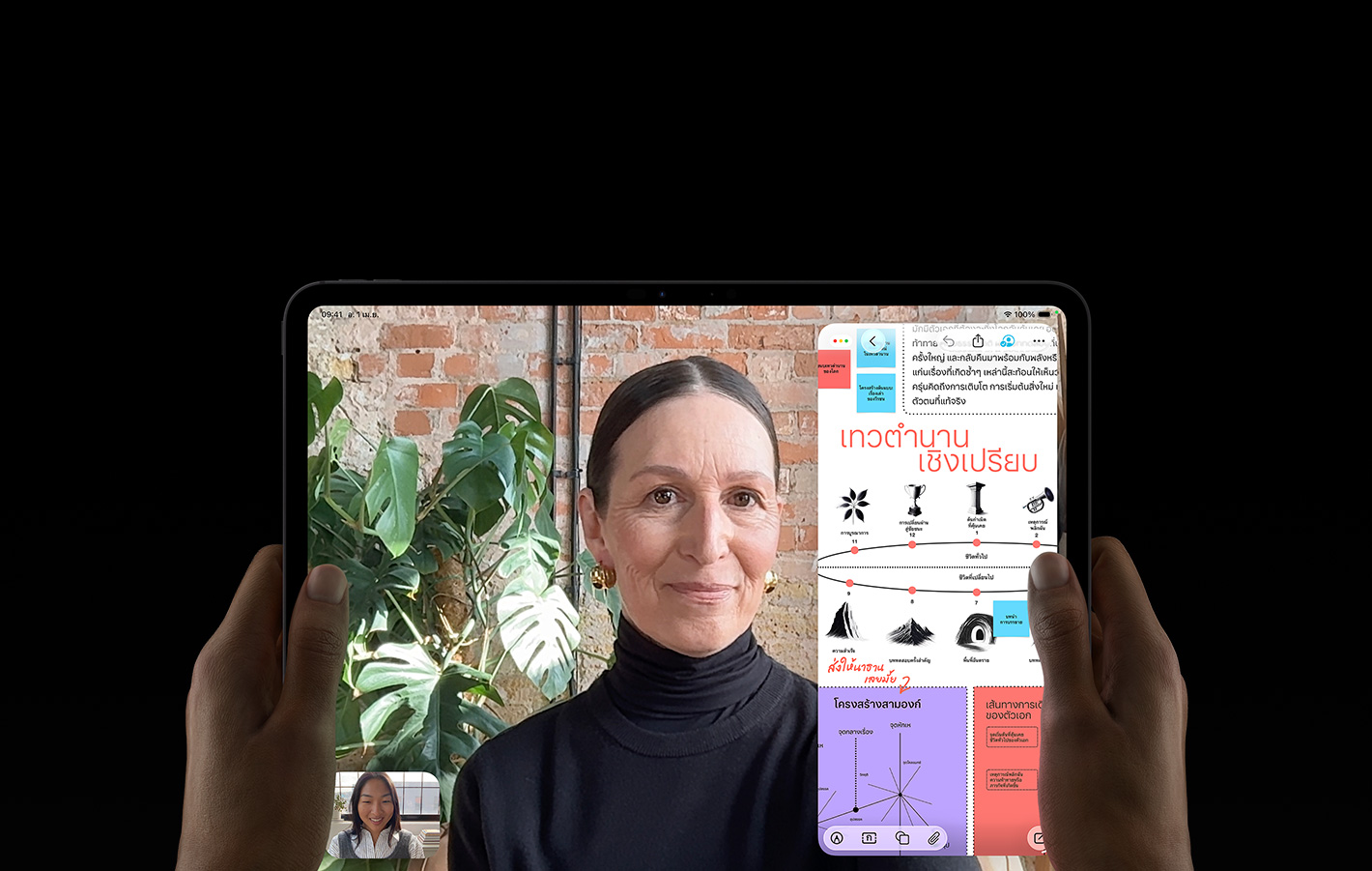 iPad Pro, front exterior, space black color, left and right hands holding in landscape orientation, rounded corners, black display bezel, display showing a FaceTime conversation being live translated, and an educational app showing a presentation of 'Comparative Mythology' with text, diagrams, and handwritten notes