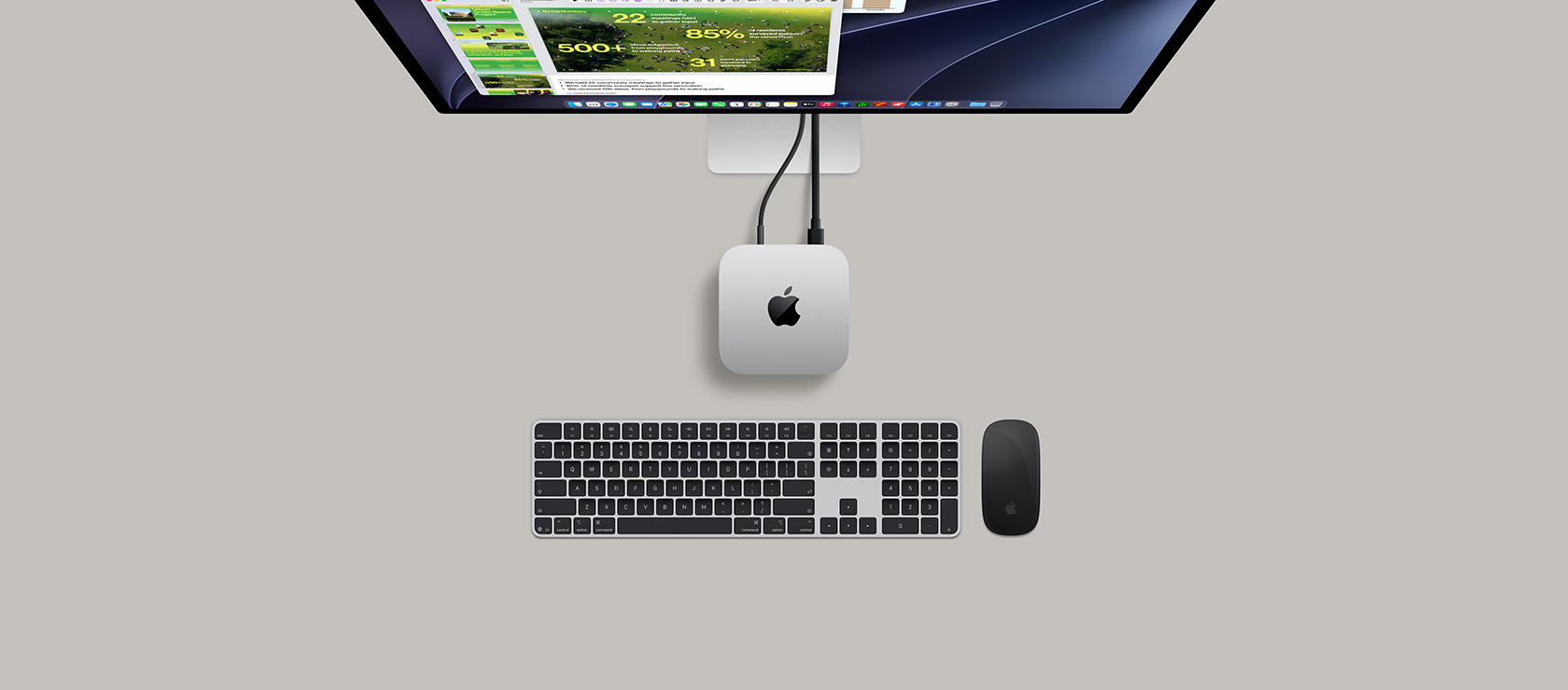 Mac mini, top, silver aluminum, rounded corners, glossy black Apple logo centered, connected by cord, Studio Display partially visible on top with screen showing Calendar app, Keynote presentation, and bar graph open, Magic Keyboard with Numeric Keypad, Magic Mouse visible below Mac mini