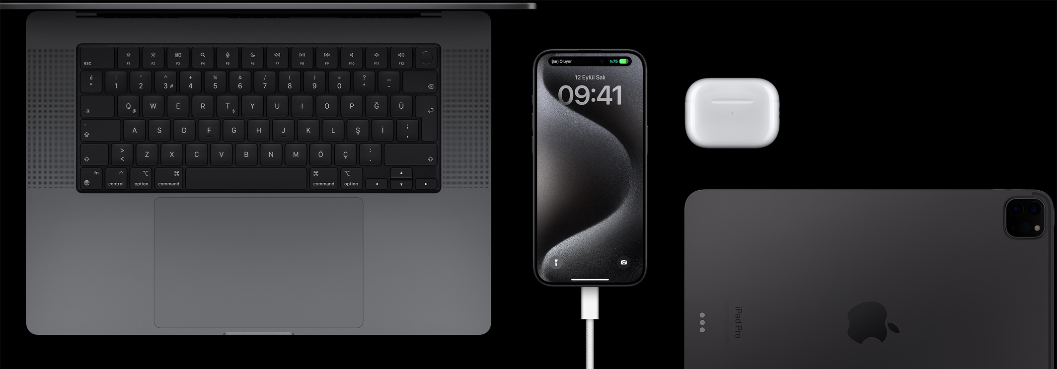 Bir MacBook Pro, AirPods Pro ve iPad ile çevrelenmiş, USB-C kablosunun takılı olduğu iPhone 15 Pro