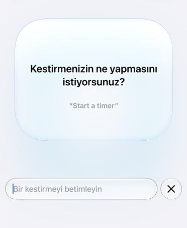 Ekranda bir Apple Intelligence isteği gösteriliyor. Kestirme özelliği kullanıcıya “What do you want your shortcut to do?” diye soruyor. Örnek bir istek olarak “Start a timer” ifadesi gösteriliyor.”