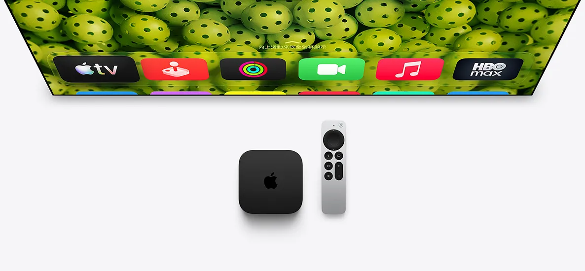 Apple TV 4K 和 Siri Remote 放在電視螢幕下方，螢幕顯示主畫面頂部的一排 app 圖像在綠色匹克球背景上方