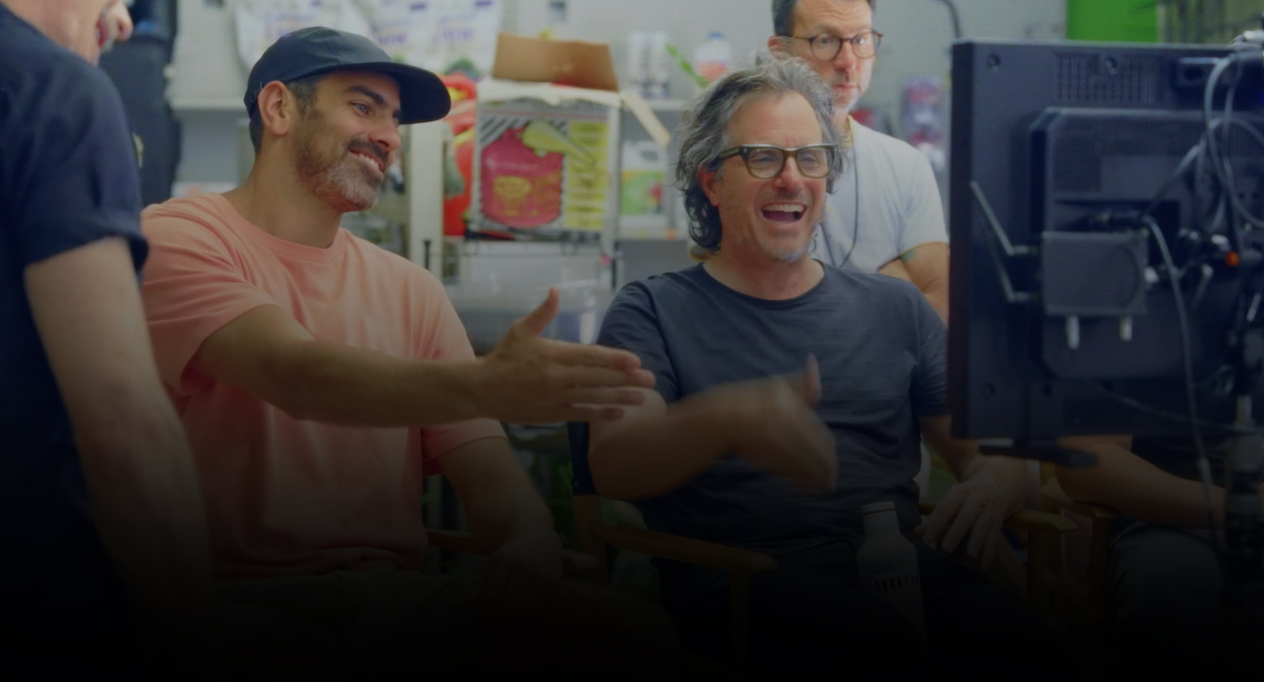 Image of two seated male filmmakers watching and gesturing to projection screen.
