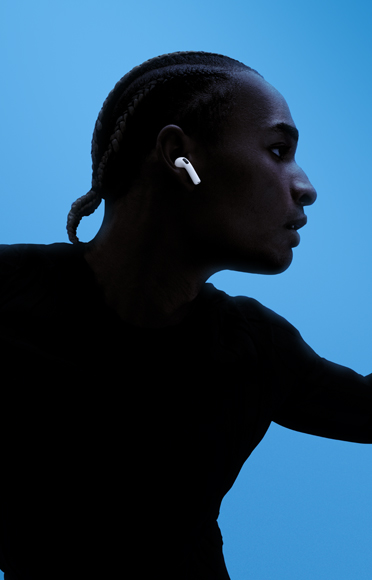 A person wearing AirPods 5, arms spread, coloured background
