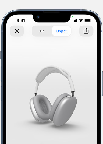 Obraz przedstawia srebrne słuchawki AirPods Max w rzeczywistości rozszerzonej na ekranie iPhone’a.