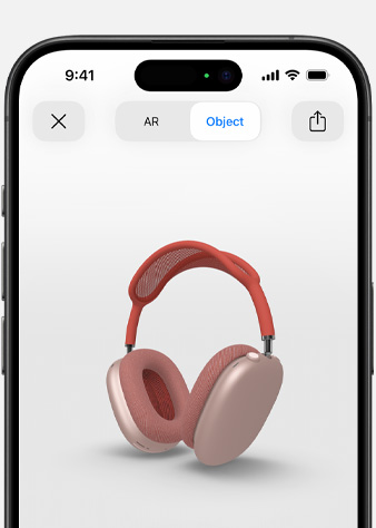 Attēlā redzamas rozā AirPods Max paplašinātās realitātes ekrānā uz iPhone.