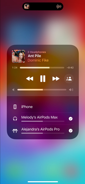 AirPods Pro I ladesak ved siden av iPhone er iPhone koblet til to sett med AirPods, hver med individuell volumkontroll