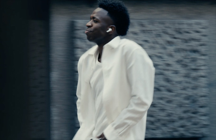 Person outside wearing white shirt, left AirPods Pro 3 earbud visible