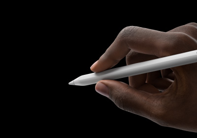 La mano de un usuario sostiene un Apple Pencil Pro en posición para escribir. La punta se orienta hacia una interfaz que muestra una nueva paleta de herramientas.