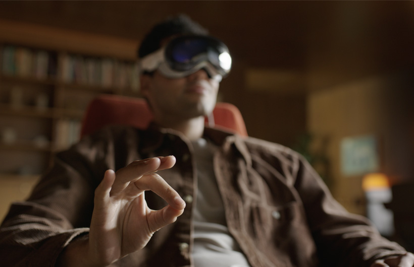 A person seated taps their fingers to trigger an action in visionOS