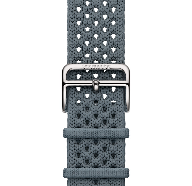 Correa Néo Tricot para el Apple Watch Hermès Series 11, correa Néo Tricot, color Bleu Gris (gris azulado), confeccionada con hilo de poliamida tejido, orificios de ajuste en el centro, cierre de hebilla en plata con grabado de Hermés