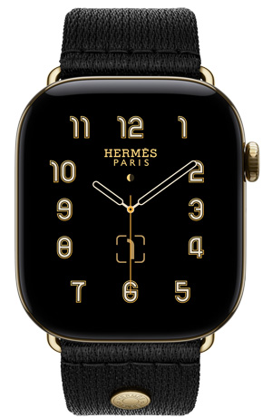 Apple Watch Hermès Series 12, Clou de Selle analogue watch face (hour, minute and second hands, complications: lunar phase, date), titanium case, radiant gold colour, right side exterior, Digital Crown, side button, paired with Noir Satin Clou de Selle strap, smooth black satin webbing with radiant gold hardware that matches the watch case