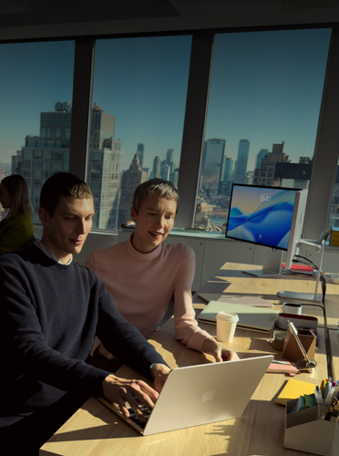 Two colleagues collaborate on MacBook Air in an office, emphasizing how MacBook Air is the leading laptop for business