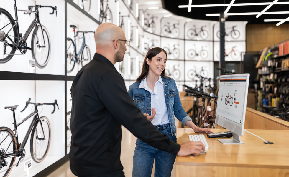 Julien Sicuro, responsable de magasin, présente à une cliente les choix de vélos sur le splendide écran Retina d’iMac.