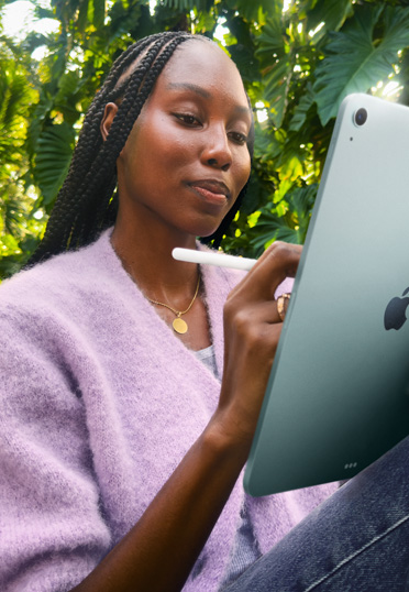 Eine Studentin, die im Freien sitzt. Sie hält ein iPad und einen Apple Pencil Pro in den Händen.