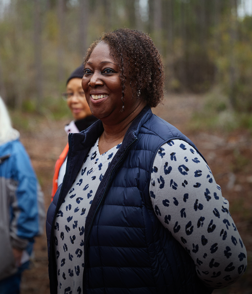 Mujeres negras sonrientes y otras personas en un bosque