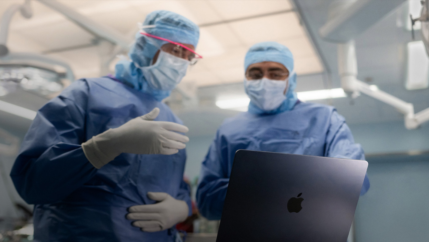 جراحان يناقشان أمراً على شاشة MacBook Pro في غرفة العمليات.