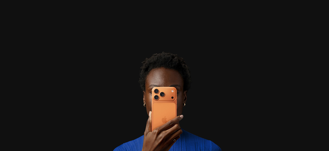 Una persona sostiene un iPhone 17 Pro frente a su cara, con la parte trasera hacia afuera, color naranja cósmico.