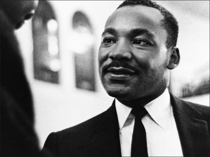 Black and white photo of Dr. Martin Luther King Jr. listening intently, in a Baptist church in Miami, Florida, January 1965.