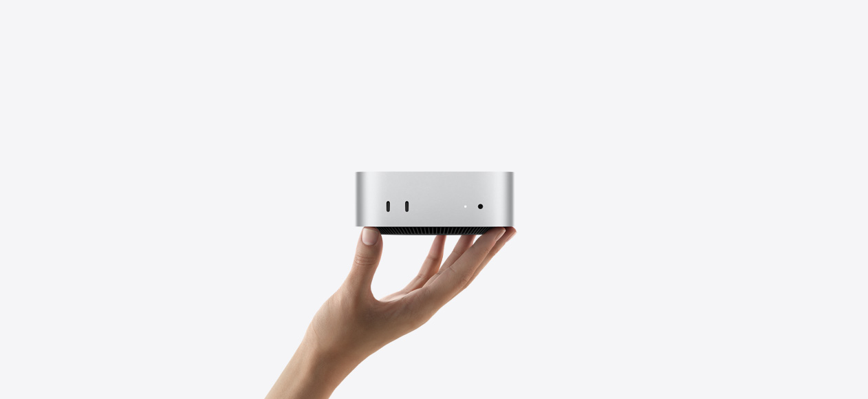 Yukarı doğru açık bir elin parmak uçları üzerinde dengede duran Mac mini’nin önden görünümü, iki adet Thunderbolt bağlantı noktası, durum göstergesi ışığı ve kulaklık jakı, altta konik tasarımlı siyah taban, düz üst yüzey, yuvarlatılmış köşeler, düz kenarlar, gümüş rengi