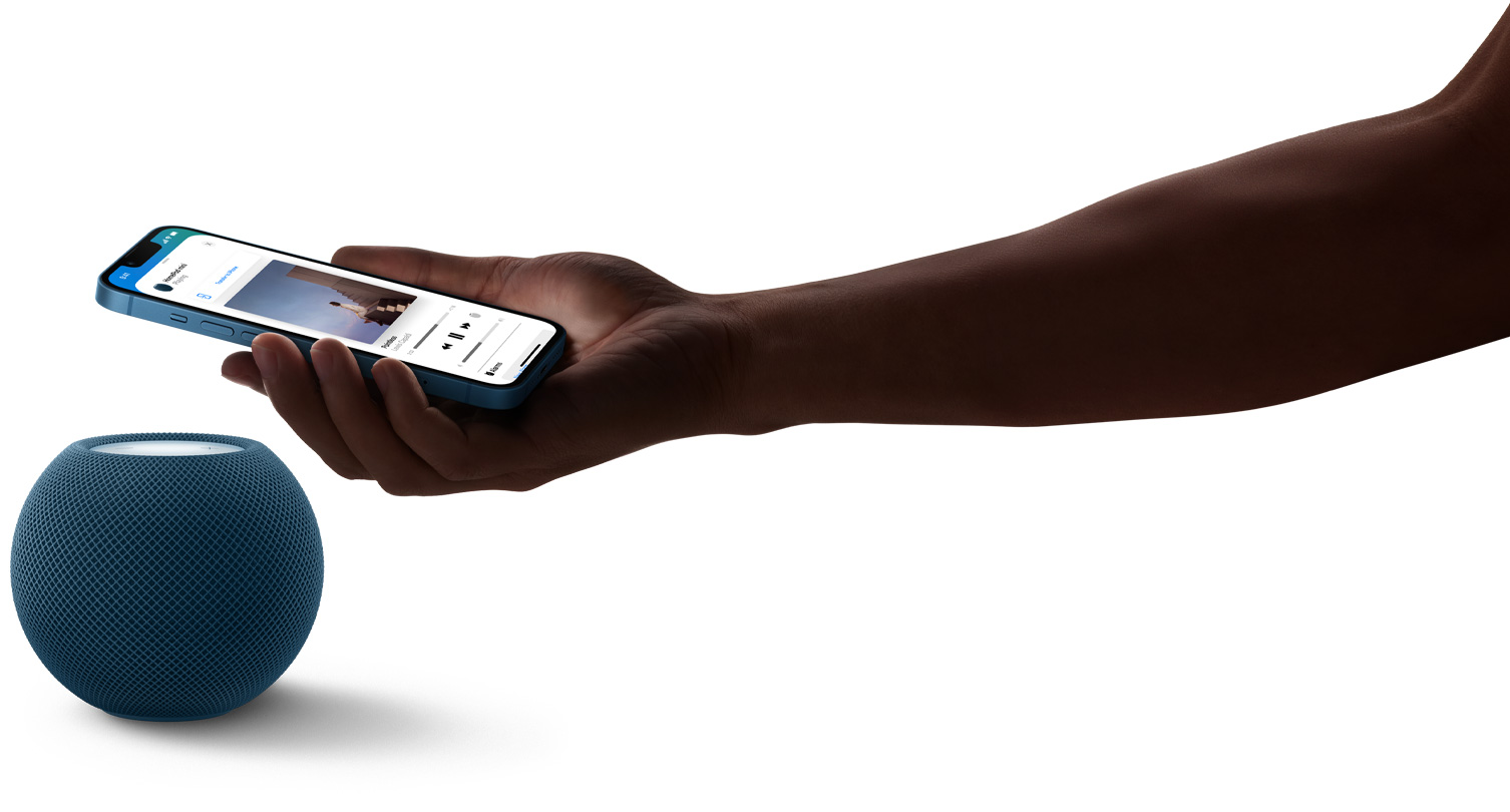 En HomePod mini i blå og en hånd som holder en iPhone over HomePod mini. Musikk spilles av på iPhone-skjermen.