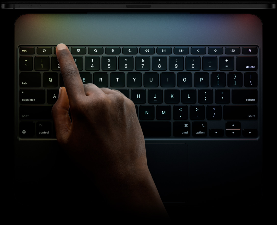 Özel işlev tuşlarına, ters döndürülmüş T biçimindeki ok tuşlarına, yerleşik trackpad’e sahip Siyah Magic Keyboard’a yatay pozisyonda iPad Pro takılı