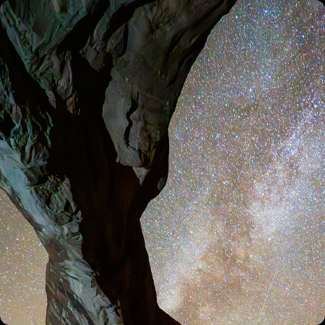 Et foto af en klippeformation med en stjerneklar nattehimmel i baggrunden