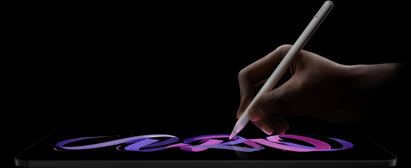 iPad Pro, parte delantera exterior, posición horizontal, perfil lateral, color negro espacial, una mano sostiene un Apple Pencil Pro blanco con el que dibuja un diseño abstracto púrpura y rosa en la pantalla