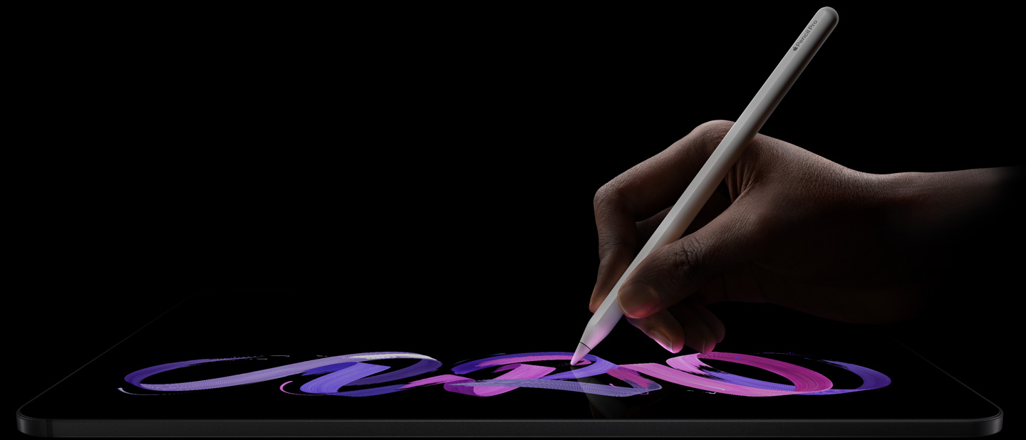 iPad Pro, parte delantera exterior, posición horizontal, perfil lateral, color negro espacial, una mano sostiene un Apple Pencil Pro blanco con el que dibuja un diseño abstracto púrpura y rosa en la pantalla