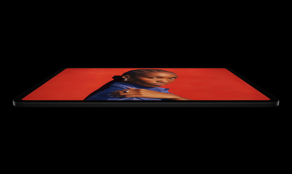 iPad Pro, lateral exterior, posición horizontal, color negro espacial, esquinas redondeadas, bisel de pantalla negro, la pantalla muestra a una persona posando con una mano sobre el hombro y una camisa azul sobre un fondo rojo brillante