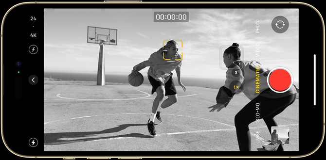 An iPhone 14 Pro screen containing a black-and-white Cinematic mode still of two people playing basketball.
