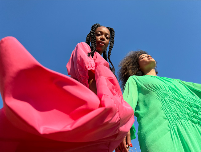 Una foto tomada con la cámara principal de dos mujeres con vestidos de colores llamativos.