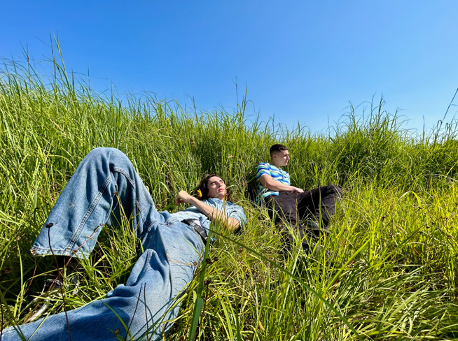 Dviejų vyrų, gulinčių žolėje, nuotrauka, nufotografuota su ultraplačiakampe kamera.