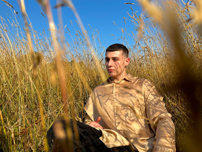 Foto van een man die tegen een helderblauwe lucht in een veld zit, genomen met slimme HDR 4.