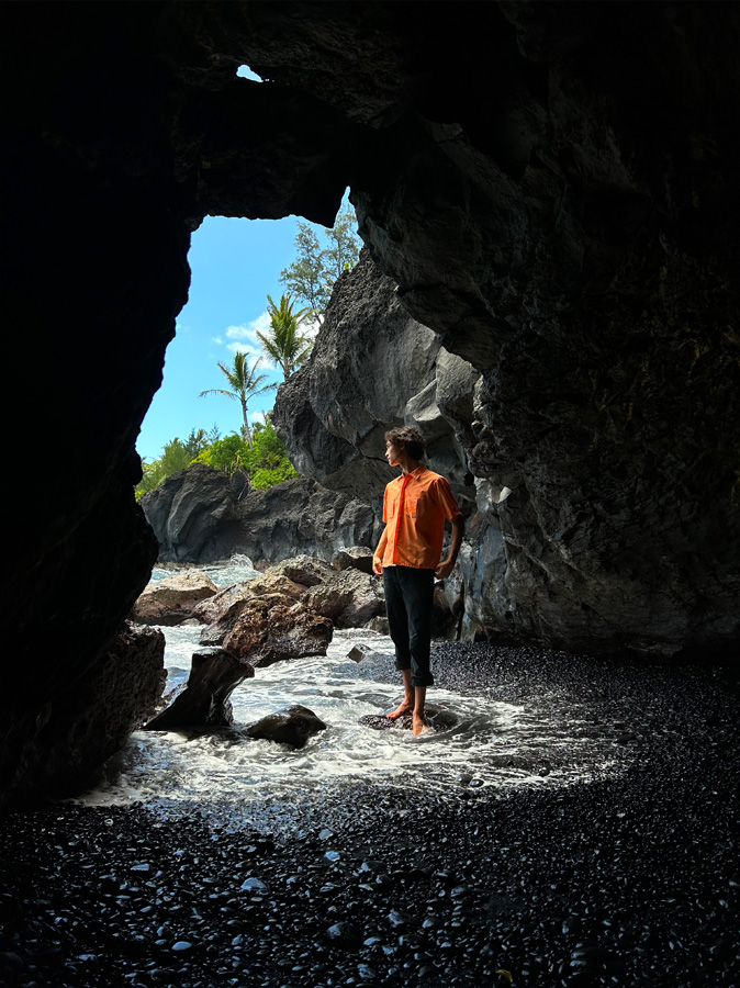 A photo of a woman standing in the entrance of a cave, taken with the Main camera.