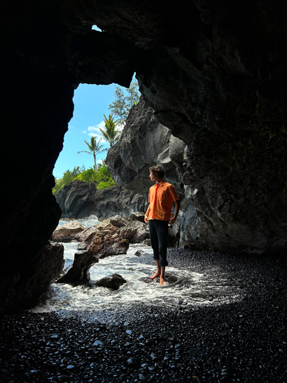一張以超廣角相機拍攝的單人照，相中人站在岩洞口。