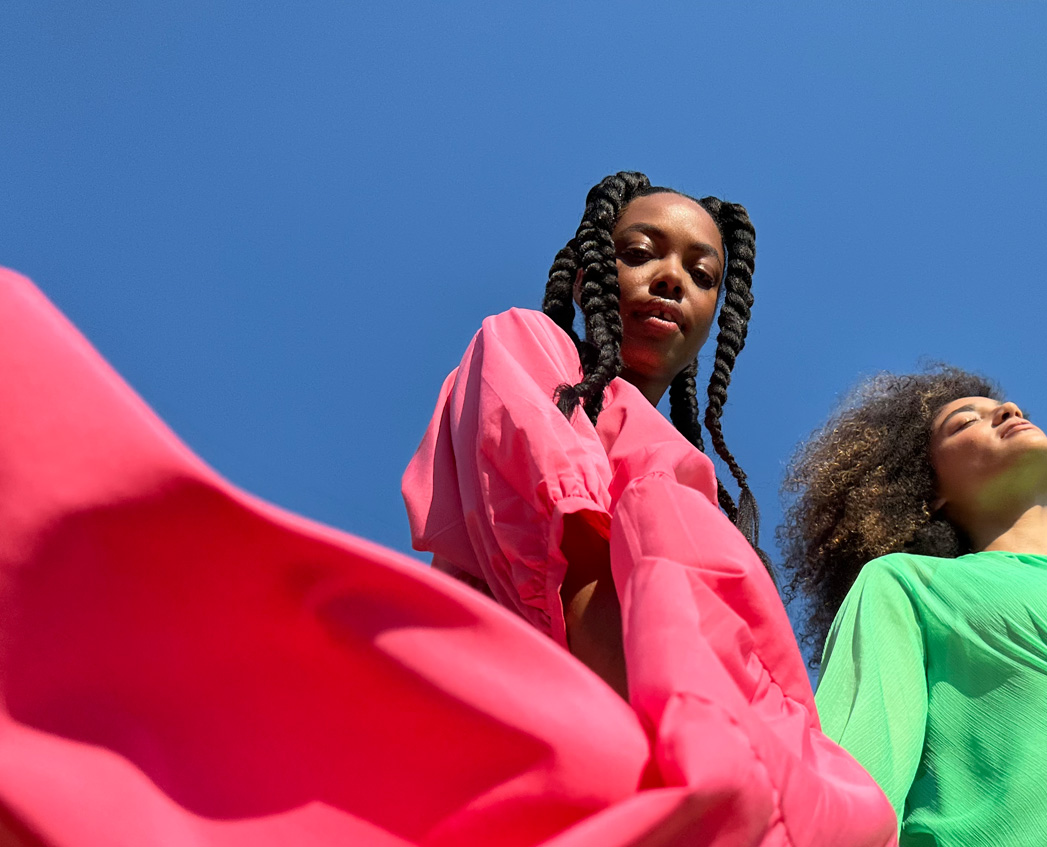 A portrait of a person wearing a bright, pink dress in the sunshine, taken with the Pro-level main camera.