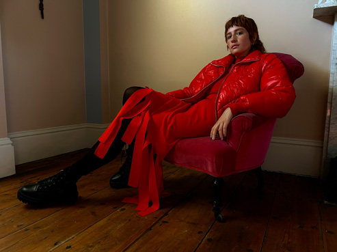 카메라의 저조도 성능을 보여주기 위해 어둑한 방에서 의자에 앉아 있는 사람을 촬영한 사진. 
