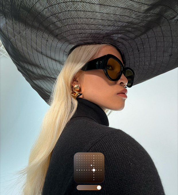 A portrait of a woman wearing a wide-brimmed black hat demonstrates the Bright Photographic Style, which brightens photos shot in low lighting conditions or Night mode