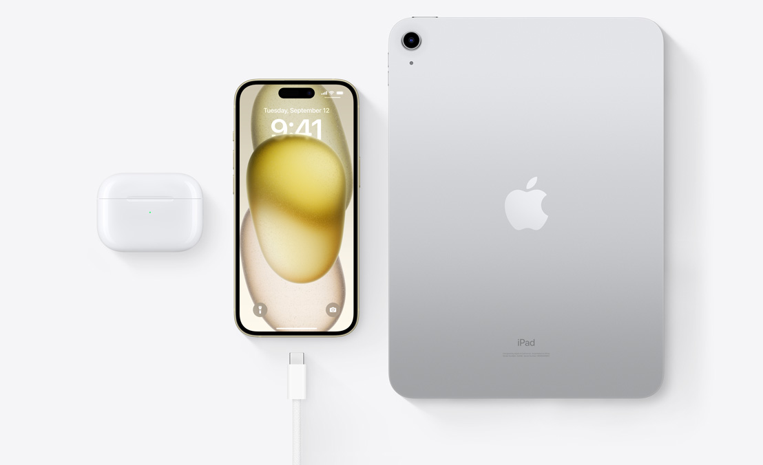 AirPods Pro、iPhone 15和带有USB-C接口的iPad的鸟瞰图，展示了如何使用同一根USB-C电缆为这三种设备充电。