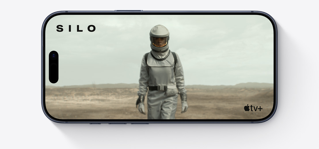 Egy fekvő tájolású iPhone elölnézetből, kijelzőjén egy űrruhás ember látható A siló című Apple TV+-sorozat egyik jelenetében