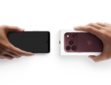 スマートフォンを交換する2つの手。左側の手が箱なしのAndroid、右側の手が箱に入った新しいバーガンディ（ダークレッド）のiPhone 18 Proを持っている
