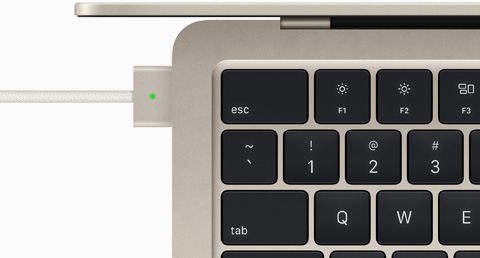 Vista superior de un cable de carga MagSafe conectado a un MacBook Air en blanco estrella.