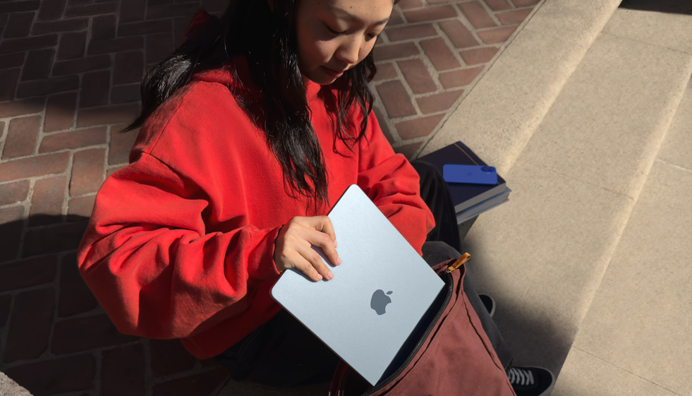 Una estudiante guardando un MacBook Air en su mochila