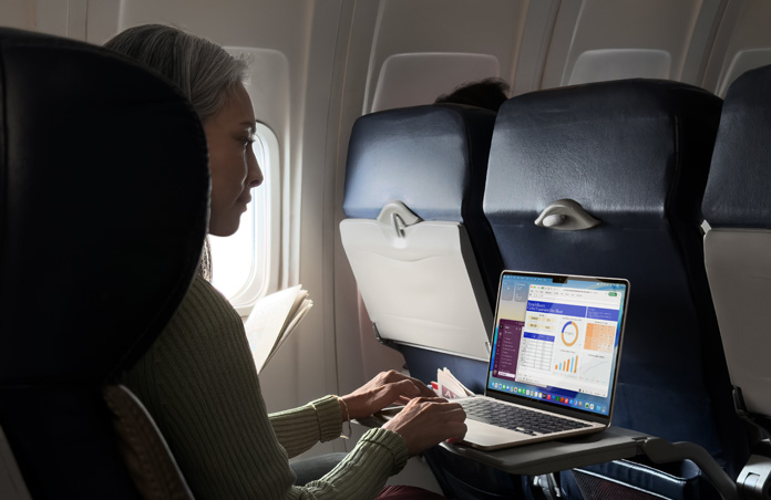 圖片展示一個人在飛機座位上使用 MacBook Air 工作