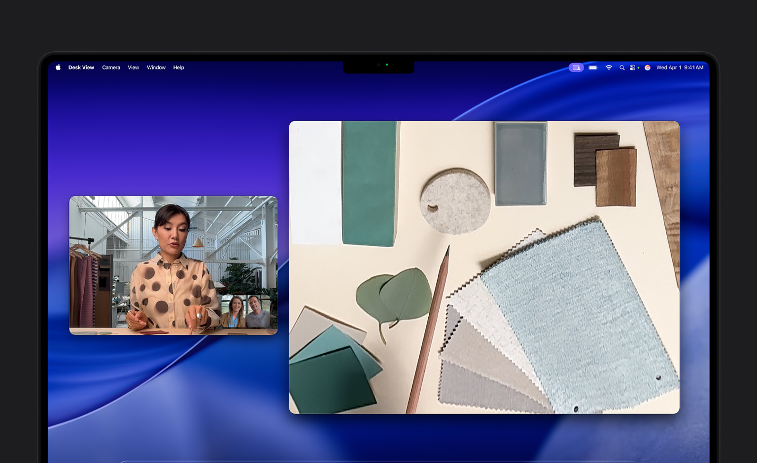 A video call on MacBook Pro of a person using the Desk View feature to show their workspace filled with fabric squares to two people on the call, Desk View lets them show their workspace and their face simultaneously
