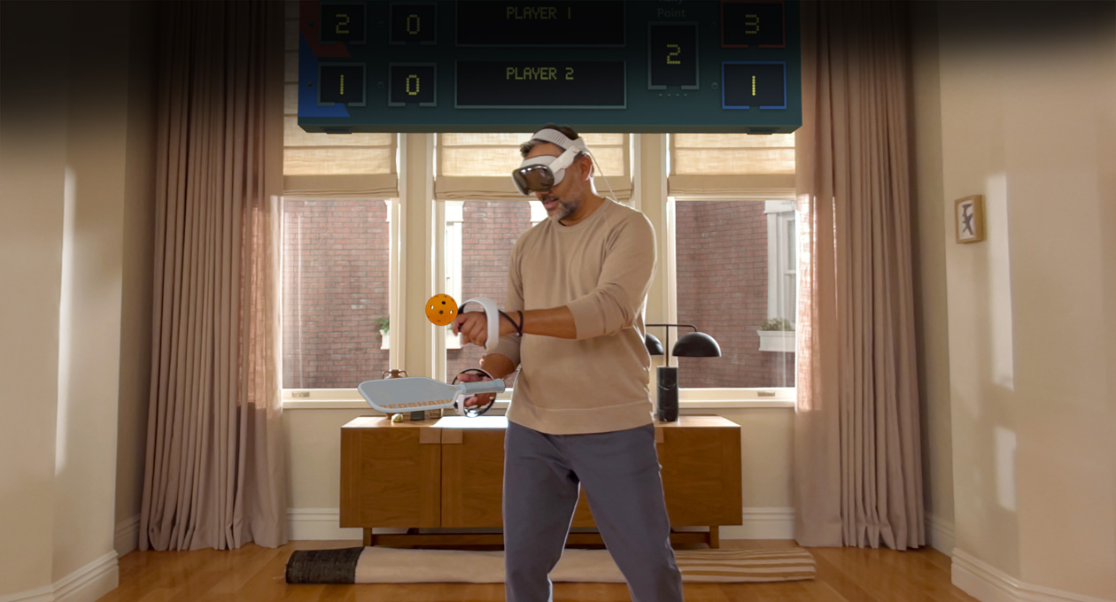 Apple Vision Proを装着してSony PlayStation VR2 Senseコントローラを使い、ゲーム「Pickle Pro」をプレイをしている男性。頭上にスコアボードが表示されている