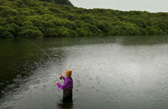 Foto seorang perempuan yang sedang fly-fishing di sungai, alat Pixelmator Pro menghapus objek yang tidak diinginkan