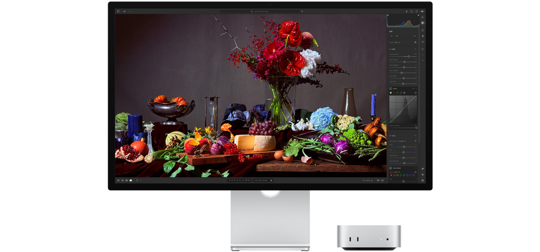 Et høykontrastbilde av et bord med diverse tallerkener med mat og en bukett mot en mørk bakgrunn, som viser hvordan TrueTone justerer fargetemperaturen.